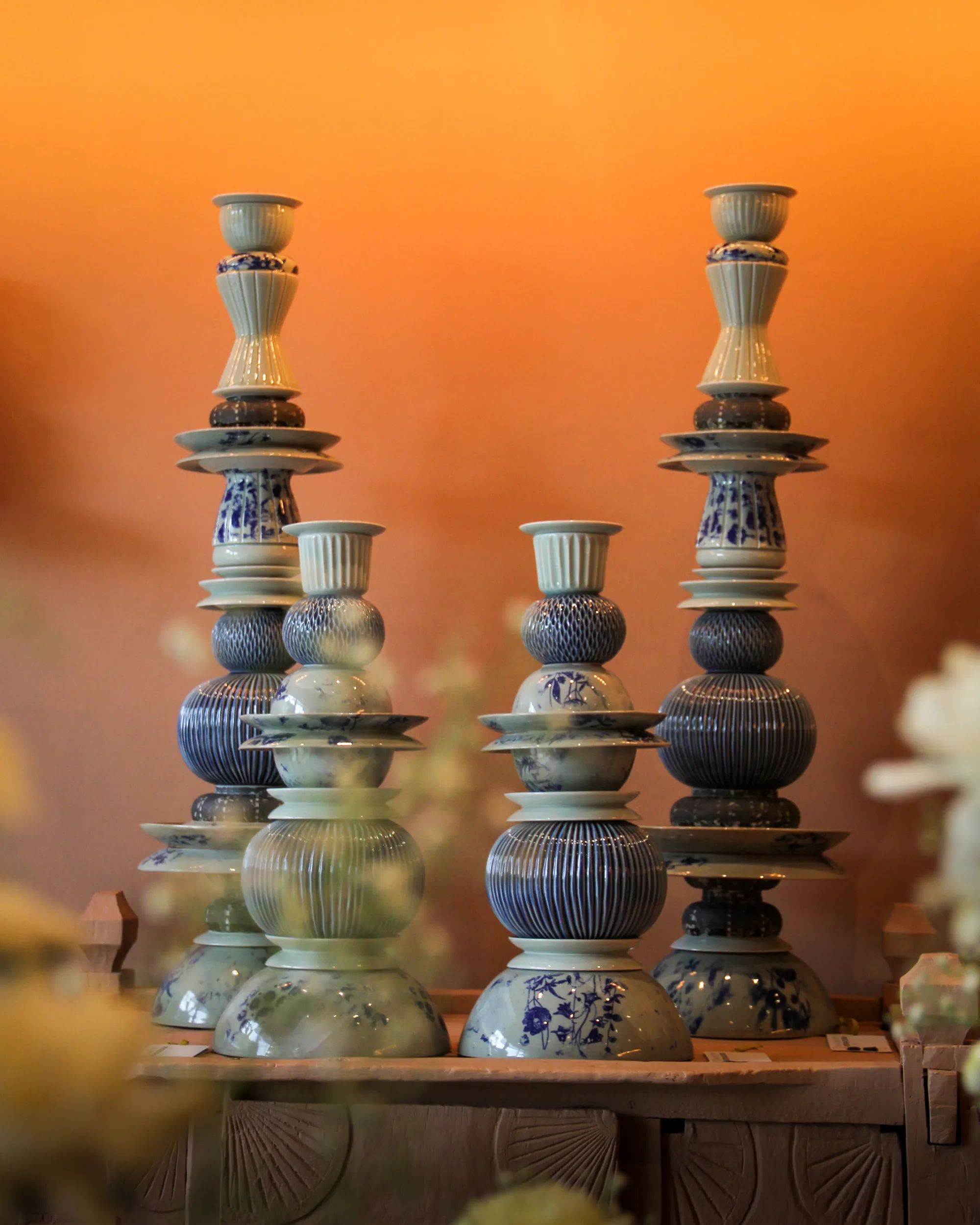 Collection of turned ceramic candlesticks against an orange wall